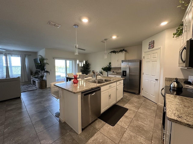 kitchen featuring a center island with sink, visible vents, open floor plan, stainless steel appliances, and a sink