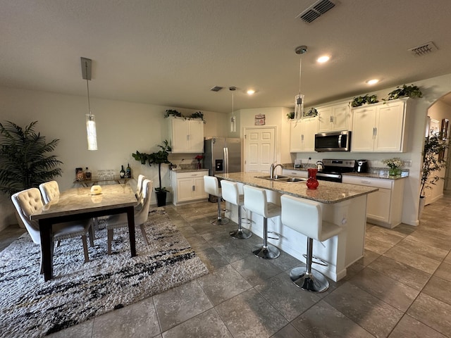 kitchen featuring visible vents, appliances with stainless steel finishes, arched walkways, and a sink