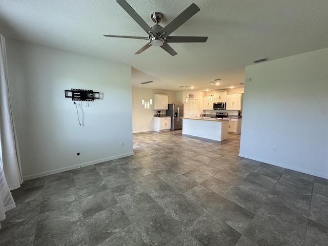unfurnished living room with a textured ceiling, ceiling fan, visible vents, and baseboards