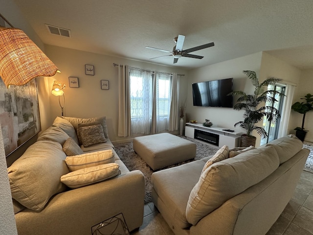 living area featuring a fireplace, ceiling fan, and visible vents