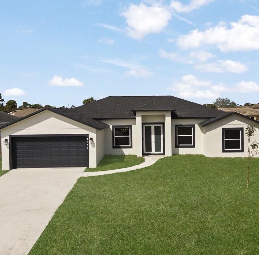 prairie-style house with a garage, driveway, french doors, a front lawn, and stucco siding