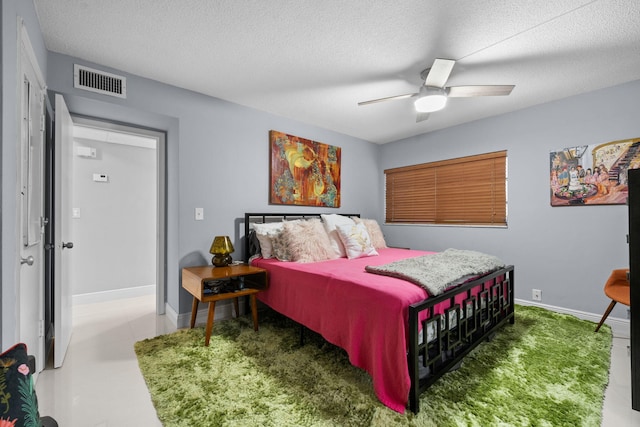 bedroom featuring a ceiling fan, baseboards, visible vents, and a textured ceiling