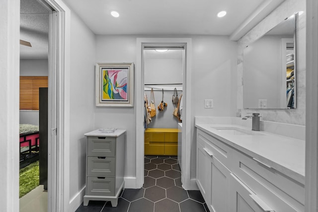 full bathroom with tile patterned flooring, recessed lighting, vanity, baseboards, and a walk in closet