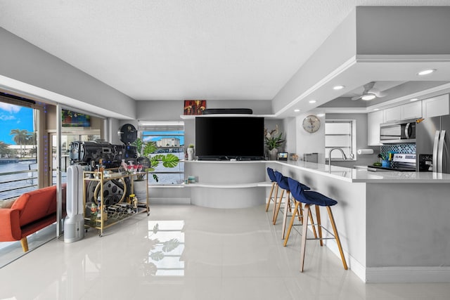 interior space featuring white cabinets, a breakfast bar area, a tray ceiling, stainless steel appliances, and light countertops