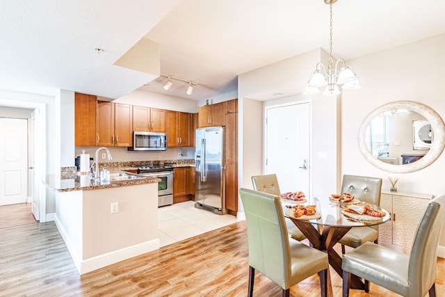 kitchen featuring brown cabinets, light stone countertops, stainless steel appliances, and a sink