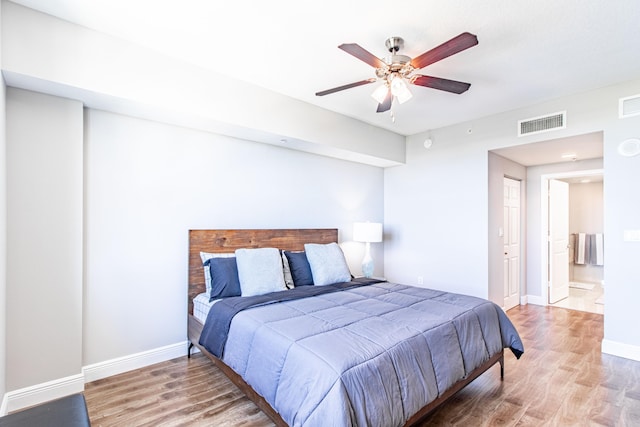 bedroom featuring a ceiling fan, wood finished floors, visible vents, and baseboards