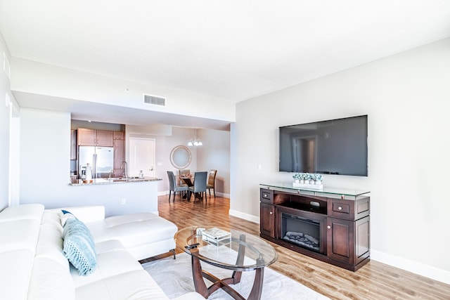 living room featuring visible vents, light wood-type flooring, and baseboards