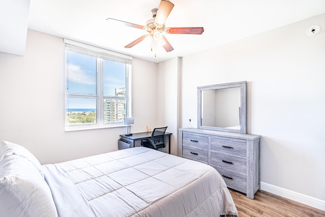 bedroom with light wood-type flooring, baseboards, and ceiling fan