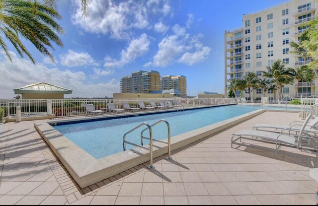 pool with a view of city, a patio, and fence