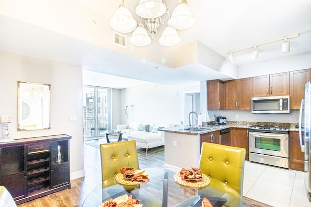 kitchen featuring visible vents, a peninsula, a sink, appliances with stainless steel finishes, and open floor plan