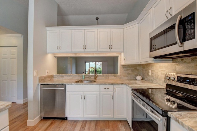 kitchen with appliances with stainless steel finishes, a sink, light wood-style floors, and white cabinets