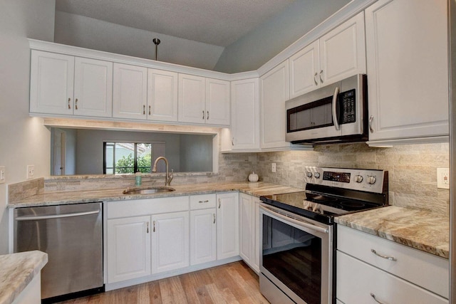 kitchen with backsplash, white cabinetry, stainless steel appliances, and a sink