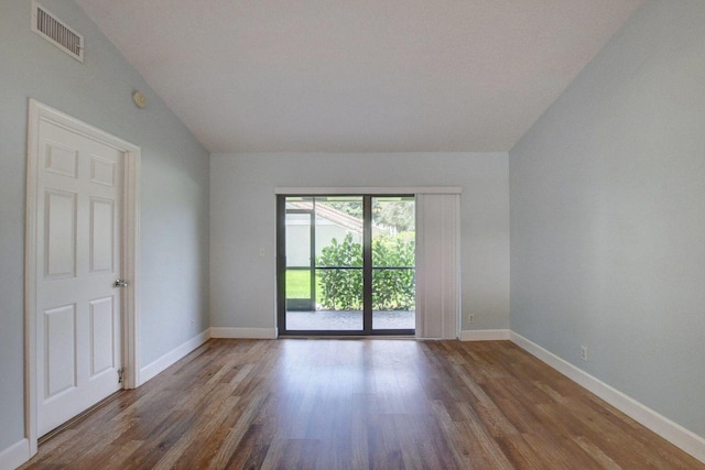 unfurnished room featuring lofted ceiling, baseboards, visible vents, and wood finished floors