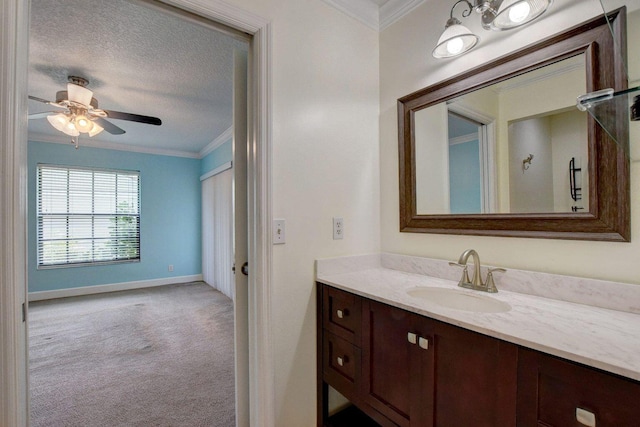 bathroom featuring a textured ceiling, a ceiling fan, baseboards, vanity, and crown molding