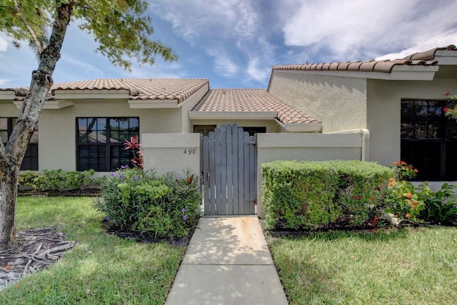 view of front of house featuring a tiled roof, a gate, and stucco siding