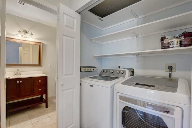 laundry room with light tile patterned floors, visible vents, washing machine and dryer, a sink, and laundry area