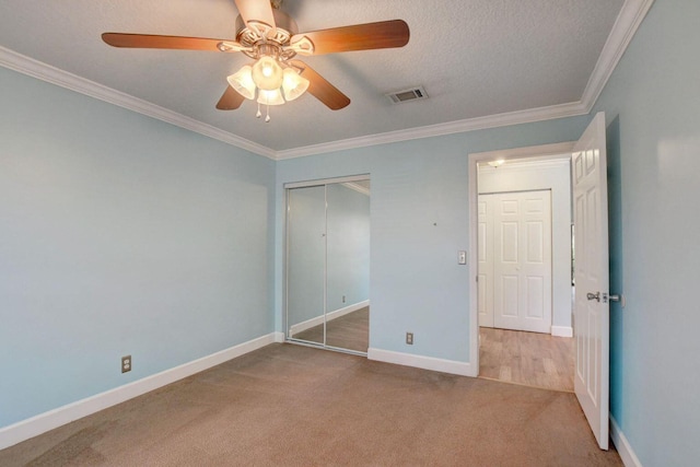 unfurnished bedroom featuring baseboards, visible vents, crown molding, carpet floors, and a closet