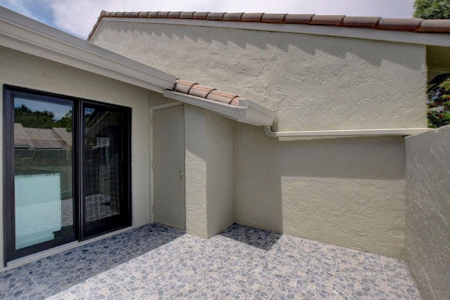 view of exterior entry with a tiled roof and stucco siding