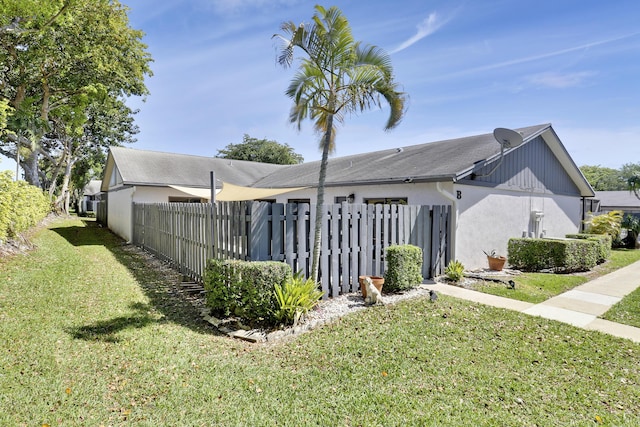 exterior space with stucco siding, a lawn, and fence