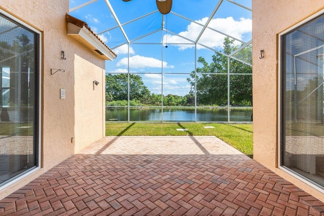 view of patio with a lanai and a water view