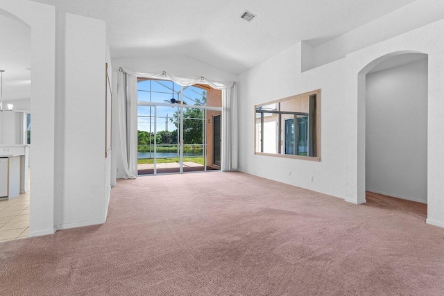 unfurnished room with arched walkways, carpet, lofted ceiling, visible vents, and a textured ceiling