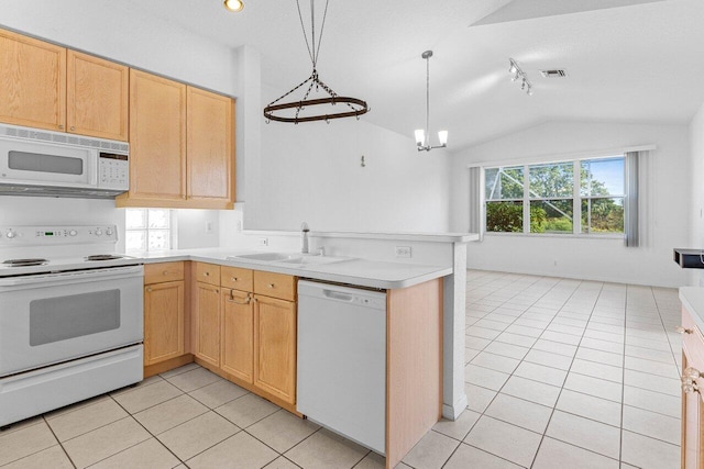 kitchen featuring light tile patterned floors, lofted ceiling, a sink, white appliances, and a peninsula