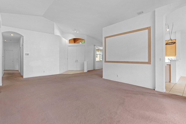 unfurnished living room with vaulted ceiling, arched walkways, carpet flooring, and visible vents