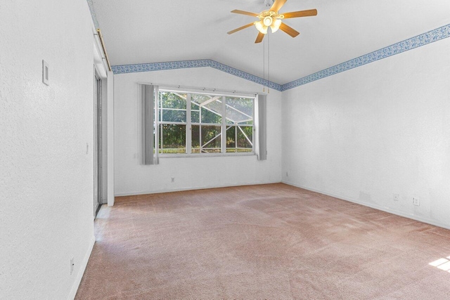 carpeted empty room featuring vaulted ceiling and a ceiling fan