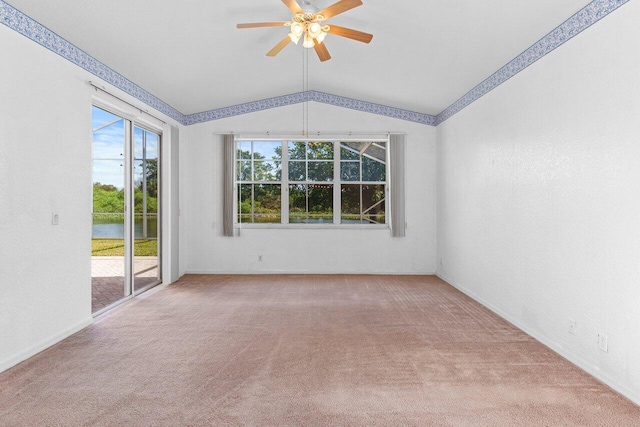 carpeted spare room with vaulted ceiling and a ceiling fan