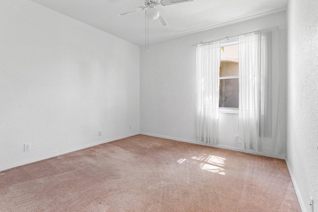 spare room with a textured wall, carpet, ceiling fan, and baseboards