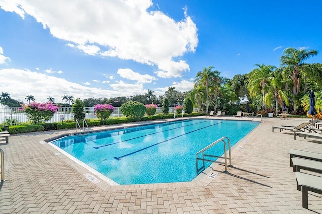 community pool with a patio area and fence