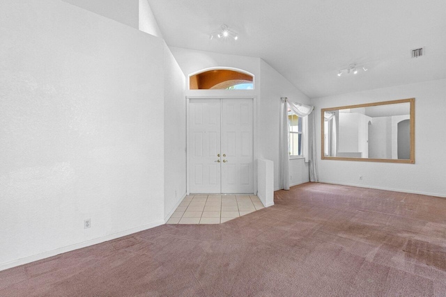 foyer with vaulted ceiling, tile patterned flooring, carpet flooring, and visible vents