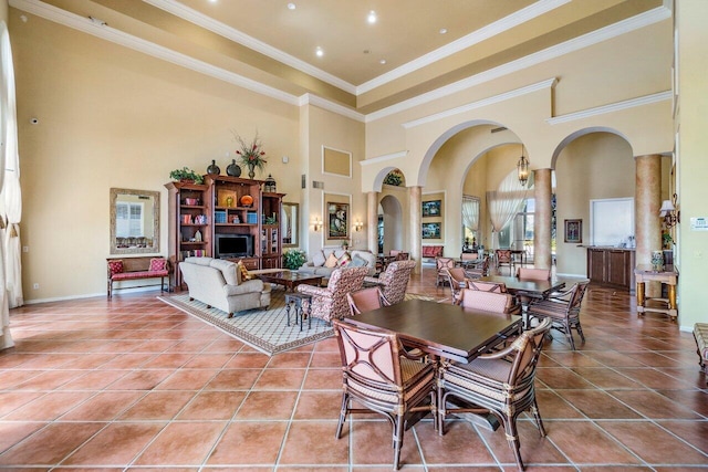 tiled dining area featuring arched walkways, ornamental molding, a high ceiling, and baseboards