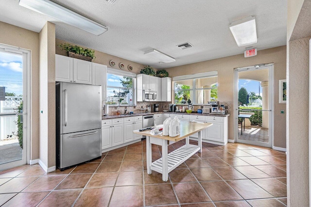 kitchen featuring stainless steel appliances, dark countertops, visible vents, and tile patterned floors