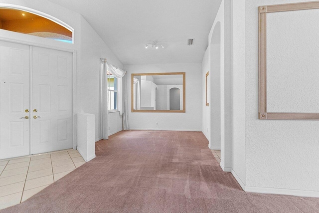 entrance foyer with lofted ceiling, carpet flooring, visible vents, tile patterned floors, and rail lighting