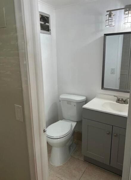 half bathroom with tile patterned flooring, vanity, and toilet