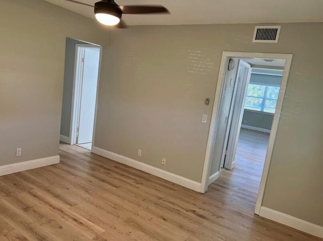 spare room with light wood finished floors, a ceiling fan, visible vents, and baseboards