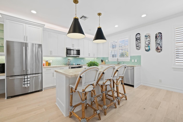 kitchen featuring visible vents, light countertops, appliances with stainless steel finishes, decorative backsplash, and light wood finished floors