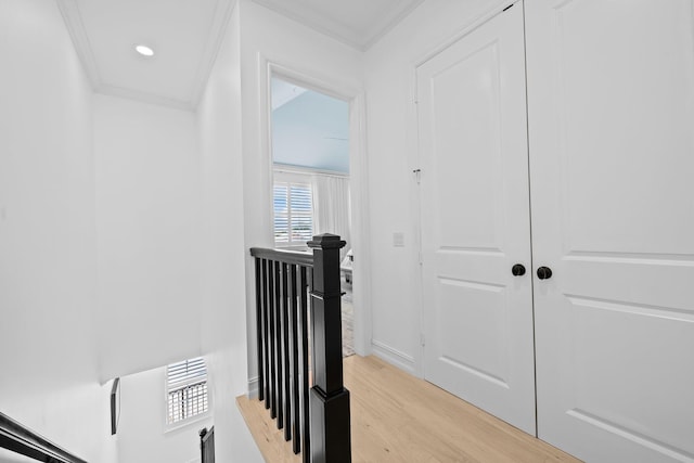 hallway with baseboards, light wood-style flooring, ornamental molding, an upstairs landing, and recessed lighting