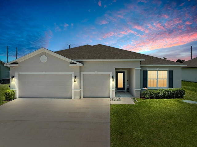 ranch-style home with stucco siding, a shingled roof, an attached garage, a front yard, and driveway