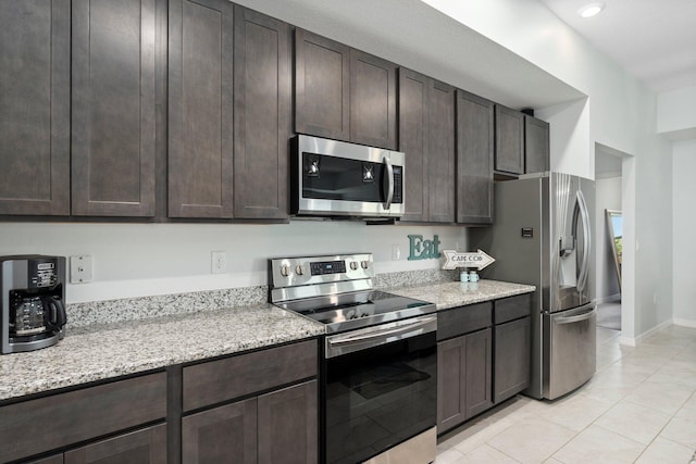 kitchen with light tile patterned floors, baseboards, light stone counters, stainless steel appliances, and dark brown cabinets