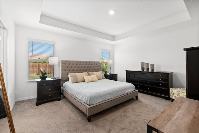 carpeted bedroom featuring baseboards and a tray ceiling