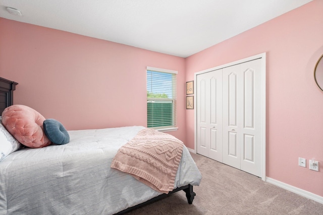 bedroom featuring a closet, light colored carpet, and baseboards