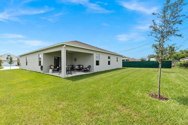 back of property with stucco siding, fence, a lawn, and a patio