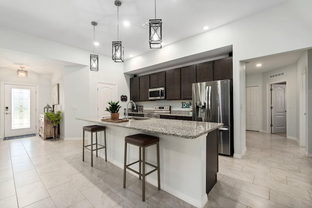 kitchen featuring dark brown cabinetry, visible vents, appliances with stainless steel finishes, a kitchen breakfast bar, and a sink