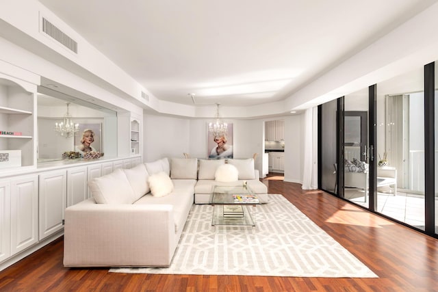 living area with dark wood-type flooring, built in features, visible vents, and a chandelier