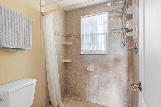 full bath with toilet and tiled shower