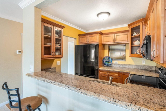 kitchen with glass insert cabinets, baseboards, light stone countertops, ornamental molding, and black appliances