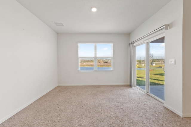 carpeted empty room with baseboards, visible vents, and a wealth of natural light