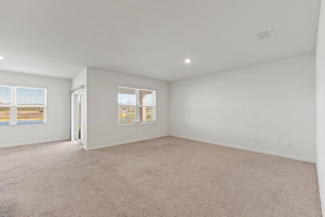 unfurnished room with baseboards, recessed lighting, visible vents, and light colored carpet